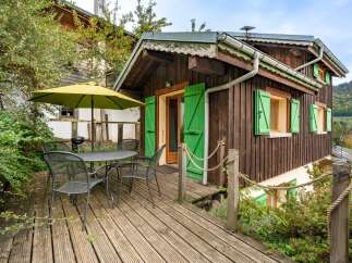 Enjoy outdoor living on this charming wooden deck, complete with a table, chairs, and a large umbrella for shade.