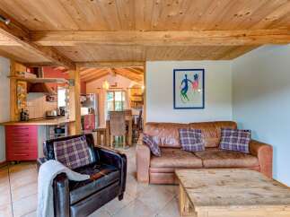 Experience rustic charm in this inviting living space featuring a cozy leather armchair and a comfortable brown leather sofa adorned with plaid cushions.