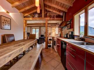 Experience rustic charm in this mountain retreat featuring a spacious wooden dining table with leather seating, perfect for family gatherings.