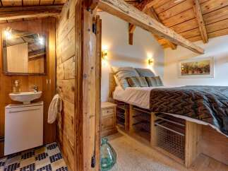Experience rustic charm in this cozy cabin bedroom, featuring a comfortable bed with a textured quilt and decorative pillows.