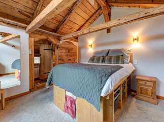 Experience rustic charm in this cozy bedroom, featuring exposed wooden beams and a vaulted ceiling that create a warm, inviting atmosphere.