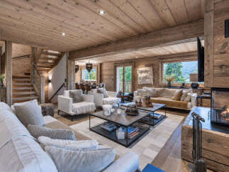 Experience luxurious mountain living in this stunning chalet-style living room, featuring a warm and inviting ambiance with exposed wooden beams and a crackling fireplace.