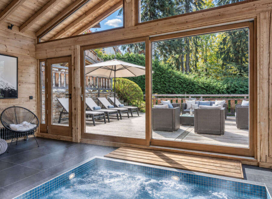 Experience ultimate relaxation in this luxurious indoor jacuzzi, featuring a stunning wooden-beamed ceiling and large glass doors that open to a private outdoor patio.