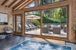 Experience ultimate relaxation in this luxurious indoor jacuzzi, featuring a stunning wooden-beamed ceiling and large glass doors that open to a private outdoor patio.