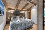 Experience ultimate comfort in this luxurious mountain chalet bedroom, featuring a plush king-size bed adorned with soft, faux fur throws and crisp white towels.