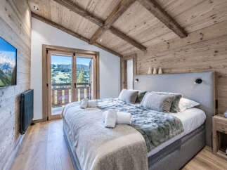 Experience ultimate comfort in this luxurious bedroom, featuring a plush king-size bed adorned with soft linens and faux fur throws.