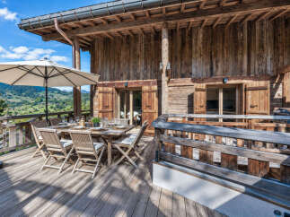Enjoy breathtaking mountain views from this stunning wooden chalet's expansive deck.