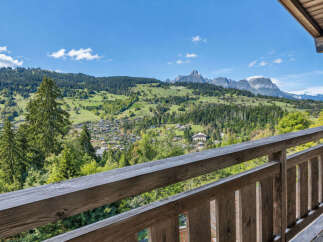 Experience breathtaking mountain views from this charming property, featuring a rustic wooden balcony perfect for enjoying the serene alpine landscape.