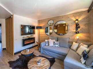 Experience cozy living in this beautifully appointed living room, featuring a modern electric fireplace set against a rustic wood-paneled wall.