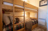 This cozy bunk bed room is perfect for families or groups, featuring comfortable bedding with a festive tartan pattern.