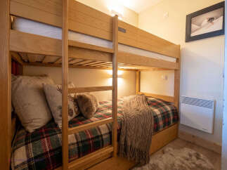 This cozy bunk bed room is perfect for families or groups, featuring comfortable bedding with a festive tartan pattern.