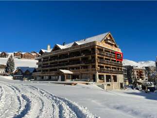 Experience luxury mountain living in this stunning ski resort property, featuring a modern wooden facade and expansive balconies perfect for enjoying breathtaking alpine views.
