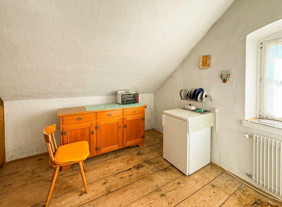 Discover this charming attic room featuring a rustic wooden floor and a sloped ceiling.
