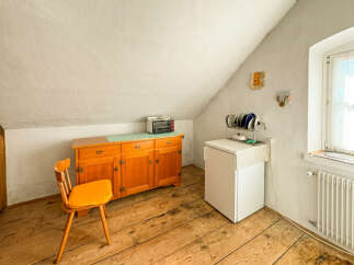 Discover this charming attic room featuring a rustic wooden floor and a sloped ceiling.