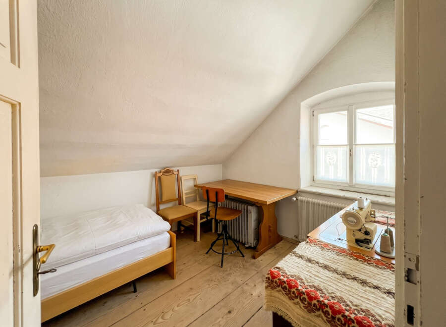Discover this charming attic room featuring a comfortable single bed with crisp white linens, perfect for a cozy retreat.
