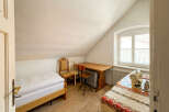 Discover this charming attic room featuring a comfortable single bed with crisp white linens, perfect for a cozy retreat.