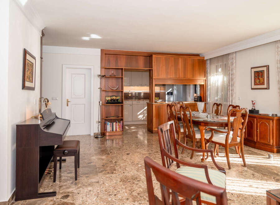 This elegant dining and living area features a rich wooden dining set with upholstered chairs, perfect for hosting gatherings.