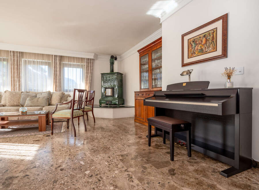 Experience elegant living in this spacious room, featuring a comfortable sofa, a stylish coffee table, and a beautiful green tiled stove.