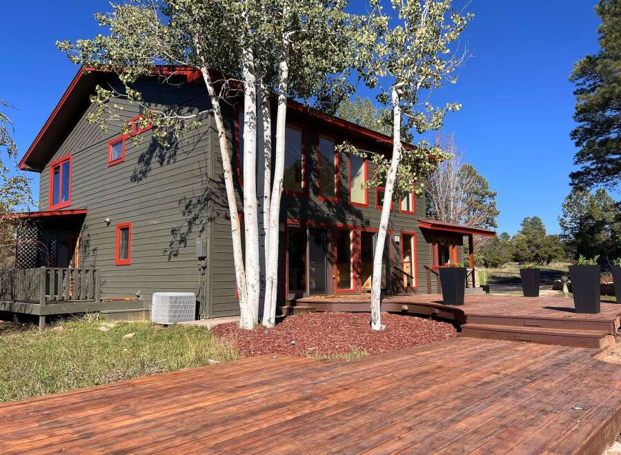 Experience the charm of this rustic home featuring a dark green exterior with striking red trim accents.