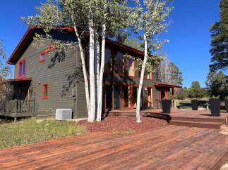 Experience the charm of this rustic home featuring a dark green exterior with striking red trim accents.