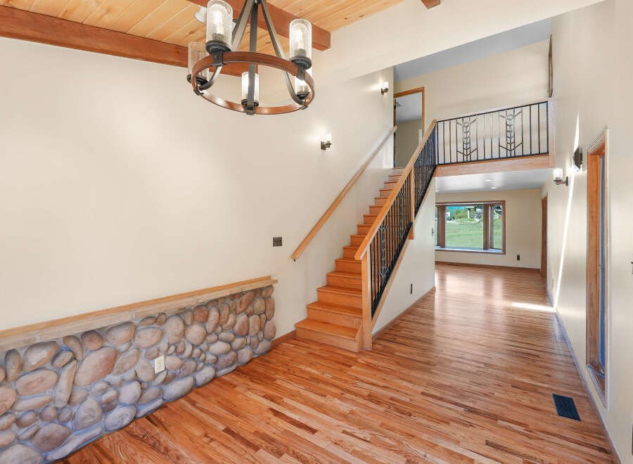 Step into this inviting entryway featuring a stunning stone accent wall and gleaming hardwood floors.