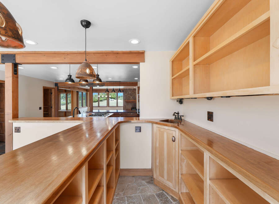 This spacious kitchen features a large wooden countertop bar with ample shelving below, perfect for entertaining.