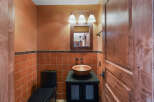 This powder room boasts a warm and inviting ambiance with its terracotta tiled walls and rich wooden accents.