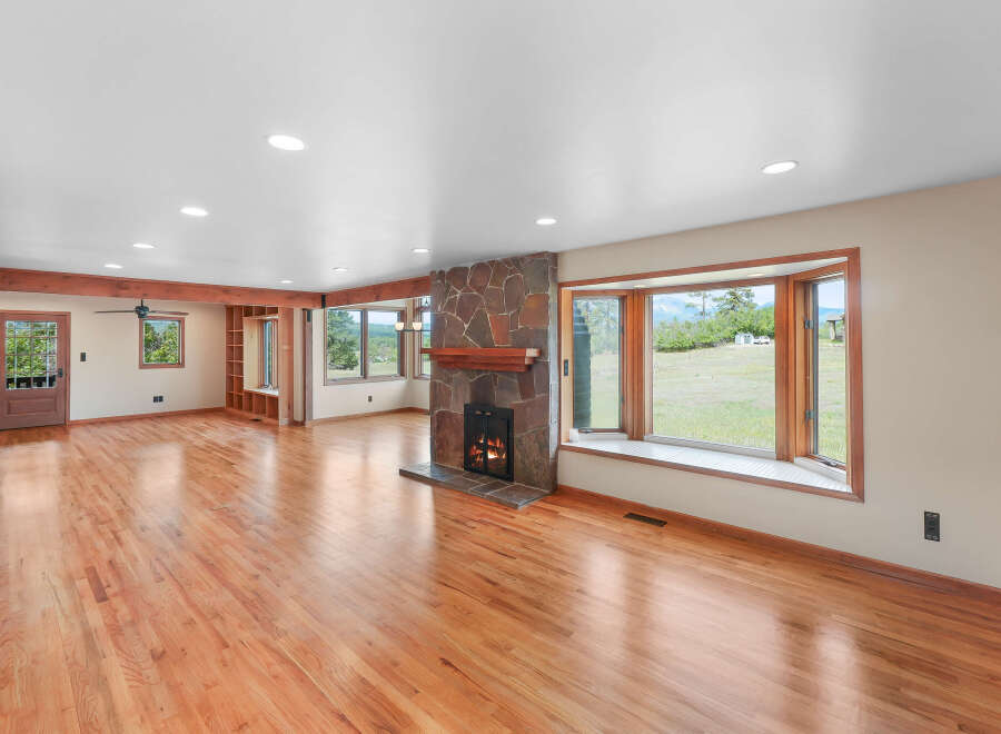 Experience breathtaking mountain views from this spacious living room, featuring a stunning stone fireplace and a large bay window.