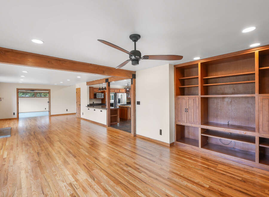 This spacious open-concept living area boasts beautiful hardwood floors and exposed wooden beams, creating a warm and inviting atmosphere.