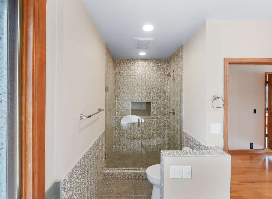 Step into this beautifully tiled bathroom, featuring a modern shower with a glass enclosure and a convenient built-in niche.