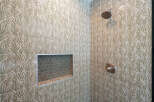 Step into a beautifully designed shower featuring elegant botanical-patterned tiles in a soothing green and beige palette.