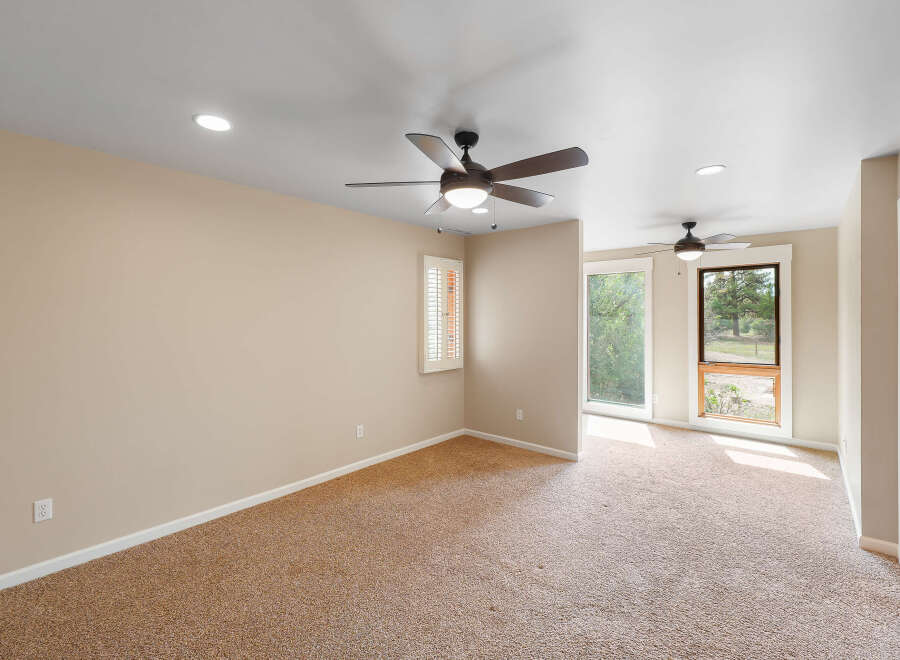 This spacious room features plush carpeting and two ceiling fans for optimal comfort.