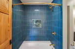 This modern bathroom features a stunning shower with vertical, deep blue tilework and a decorative mosaic accent.