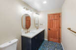 This bathroom features a spacious double vanity with a white quartz countertop and a navy blue cabinet base, complemented by brushed gold fixtures and oval mirrors.