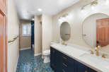 This modern bathroom features a deep navy vanity with brass hardware, complemented by a white quartz countertop and dual sinks.
