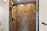 Step into a luxurious shower experience with stunning marble-look tiles in rich brown and orange tones.