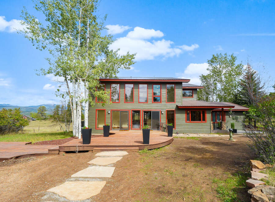 Experience modern living in this stunning home featuring a spacious wooden deck perfect for outdoor entertaining.