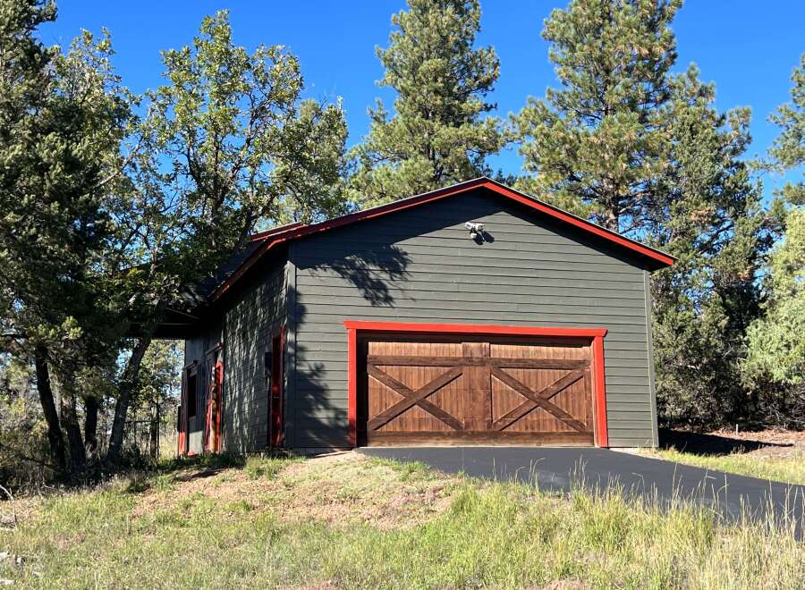 Discover this charming garage with a rustic wooden double door, accented by vibrant red trim.