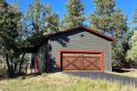 Discover this charming garage with a rustic wooden double door, accented by vibrant red trim.