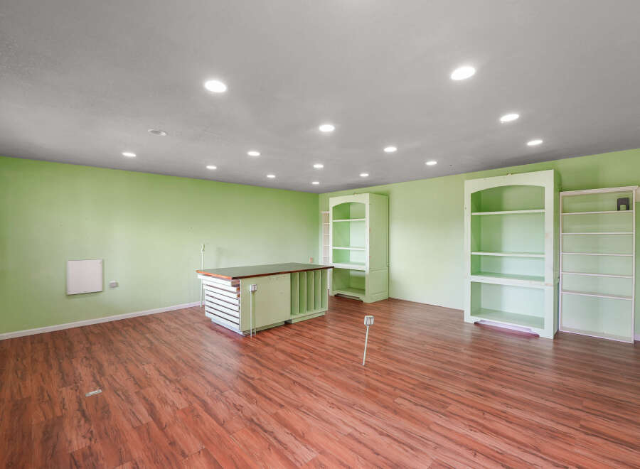 This spacious room features light green walls and a warm wood-look floor, creating a bright and inviting atmosphere.