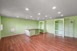 This spacious room features light green walls and a warm wood-look floor, creating a bright and inviting atmosphere.