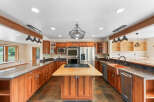 This spacious kitchen boasts custom cherry wood cabinetry, granite countertops, and a large butcher block island with a gas range.