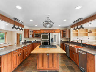 This spacious kitchen boasts custom cherry wood cabinetry, granite countertops, and a large butcher block island with a gas range.