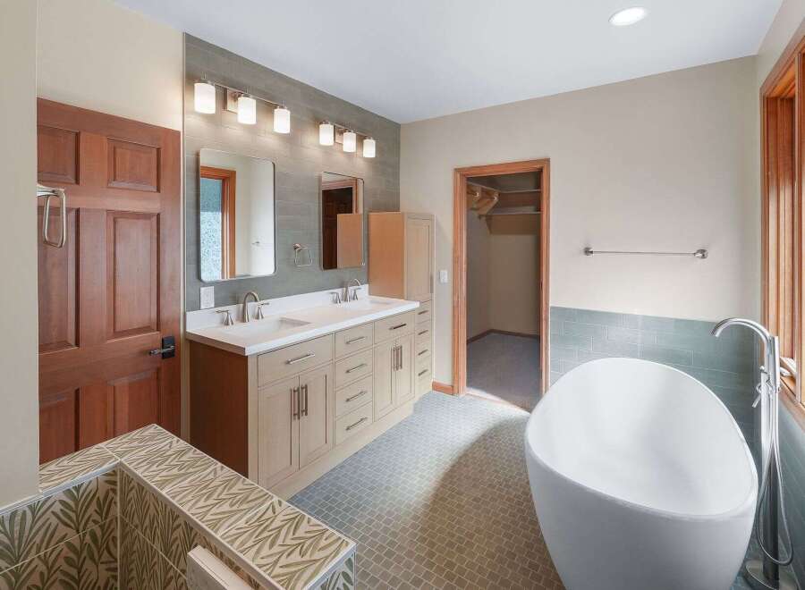 This spacious bathroom features a modern freestanding bathtub and a double vanity with ample storage.
