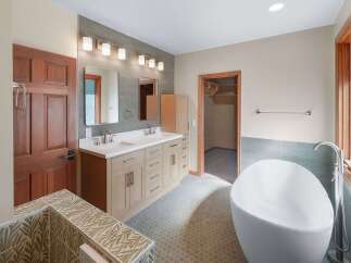 This spacious bathroom features a modern freestanding bathtub and a double vanity with ample storage.