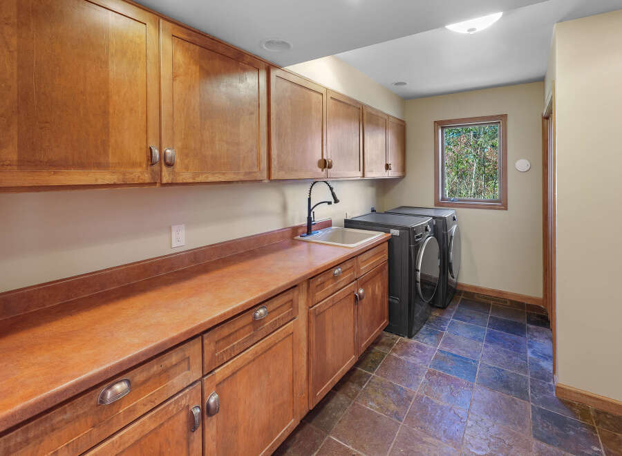 This laundry room boasts ample storage with custom wooden cabinetry, both above and below the countertop.