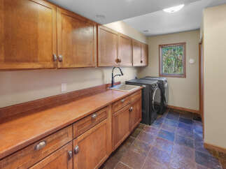 This laundry room boasts ample storage with custom wooden cabinetry, both above and below the countertop.