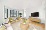 Experience modern living in this bright and airy living room, featuring large windows that flood the space with natural light and offer city views.