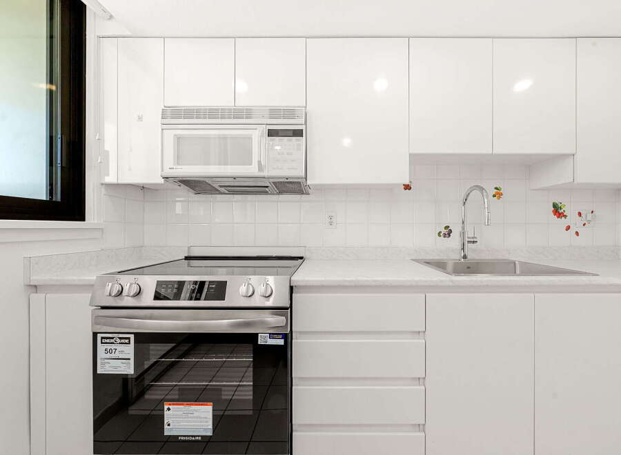 This modern kitchen boasts sleek white cabinetry and a gleaming stainless steel range, perfect for any home chef.