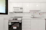 This modern kitchen boasts sleek white cabinetry and a gleaming stainless steel range, perfect for any home chef.